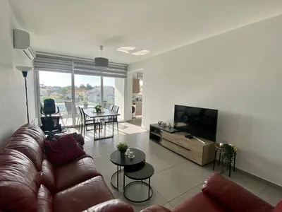 a living room with a couch and a flat screen tv at Modern 2BR near UNIC & Engomi Mall in Lakatamia