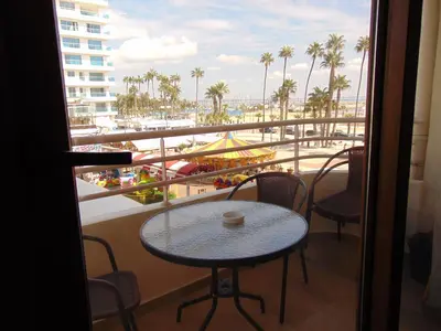 a table and chairs on a balcony with a view of the beach at Ithaki Phinikoudes Apartments No. 106 in Larnaka