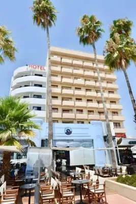 a hotel with chairs and palm trees in front of it at Ithaki Phinikoudes Apartments No. 106 in Larnaka