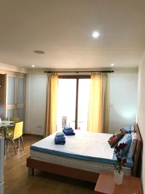 a bedroom with a bed and a table and a window at Ithaki Phinikoudes Apartment No. 107 in Larnaka