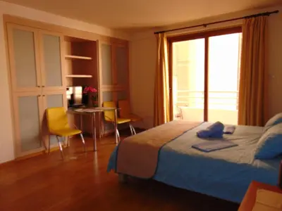 a bedroom with a bed and a table and chairs at Ithaki Phinikoudes Apartment No. 107 in Larnaka