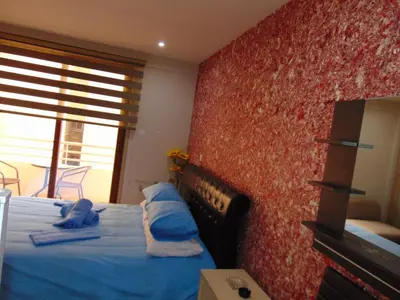 a bedroom with a bed with blue sheets and a red wall at Ithaki Phinikoudes Apartment No. 207 in Larnaka