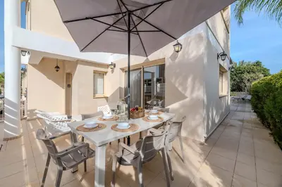 a table with chairs and an umbrella on a patio at Anthorina Greco Villa #18 in Protaras