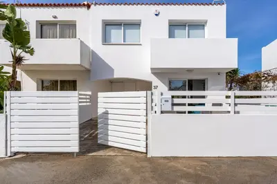 a white fence in front of a white house at Pervolia Seaview Escape in Pervolia
