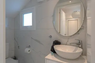 a white bathroom with a sink and a mirror at Pervolia Seaview Escape in Pervolia