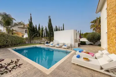 a swimming pool with lounge chairs and a villa at villa Ionion H32 in Ayia Napa