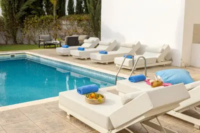 a pool with chaise lounge chairs and a swimming pool at villa Ionion H32 in Ayia Napa