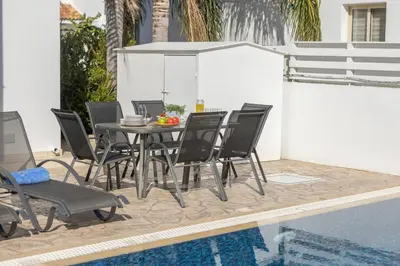 a dining table and chairs next to a swimming pool at Villa Palms 32 in Protaras