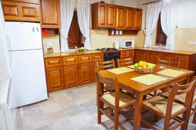 a kitchen with a wooden table and a white refrigerator at Omodos Village Houses in Omodos