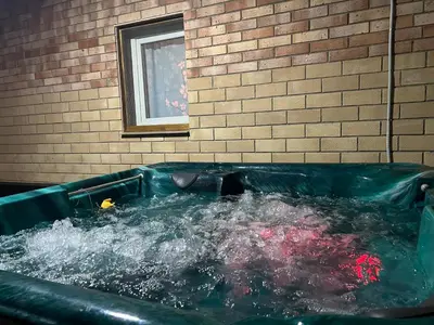 a green tub filled with water next to a brick wall at Cherry Holiday House in Khandria