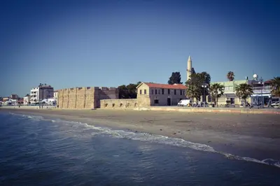 a view of the beach with a building in the background at Krasas Beach Apartment Rentals in Larnaka