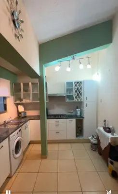 a kitchen with white cabinets and a green wall at Bar street apartment in Ayia Napa