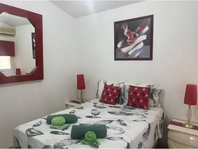 a bedroom with a bed with green pillows and a mirror at Bar street apartment in Ayia Napa