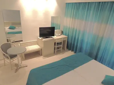 a bedroom with a bed and a desk with a television at Anesis Hotel in Ayia Napa