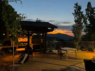 a patio with a table and a grill with a sunset at Orama Mountain Villa Farmakas in Nicosia