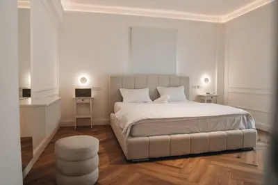 a white bedroom with a large bed and a stool at Hyperion Boutique Villa in Voroklini