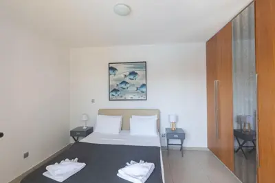 a bedroom with a bed with white sheets and two tables at Ayia Napa Satin Villa SVI3 in Ayia Napa