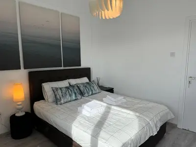 a bedroom with a bed with a white bedspread and a lamp at White 1-bdr apartment Agyos Tychonas in Limassol