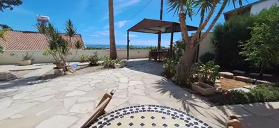 a patio with a table and chairs and palm trees at Lydia's Sea View - 2 bed House in Episkopi Lemesou