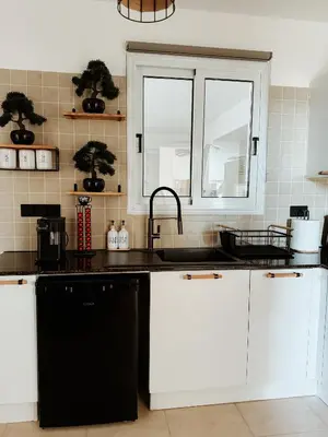 a kitchen with white cabinets and a sink and a window at Nissi Si Lux Boho Apartment on Nissi beach in Ayia Napa