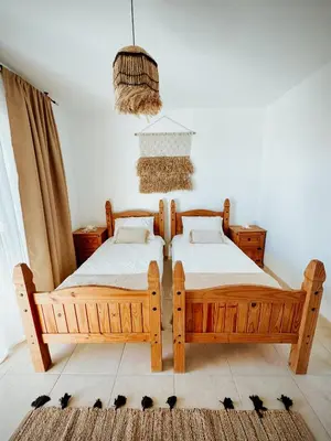 two wooden beds in a bedroom with a rug at Nissi Si Lux Boho Apartment on Nissi beach in Ayia Napa