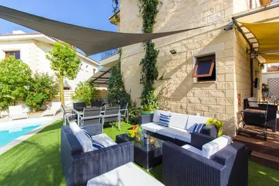 a patio with blue wicker furniture next to a pool at Gold Sand Villa in Protaras