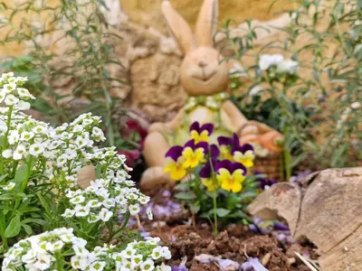 a toy rabbit sitting in a garden of flowers at The Courtyard Suite in Limassol