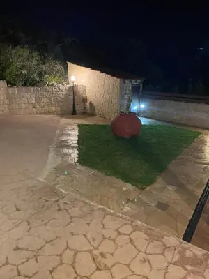 a courtyard at night with a stone wall and grass at Softades Cottage in Omodos