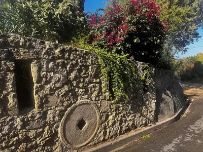 a stone retaining wall with flowers on a road at A historic STONE VILLA with private garden, terrace and private pool just for you in Kérynia
