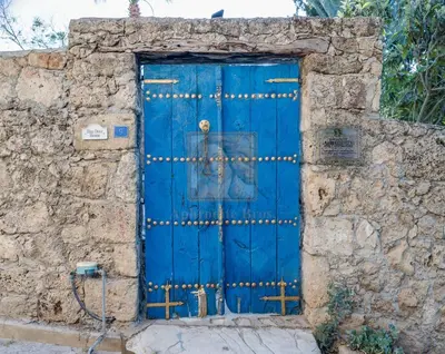 a blue door in the side of a stone wall at A historic STONE VILLA with private garden, terrace and private pool just for you in Kérynia