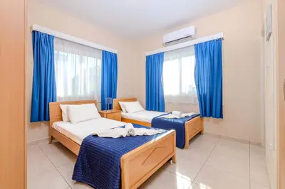 a room with two beds and blue curtains at Villa Maria in Protaras