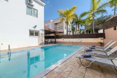 a swimming pool with chairs and a house at Villa Maria in Protaras