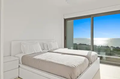a white bedroom with a bed and a large window at Serenity Waves Villa 2 in Larnaka