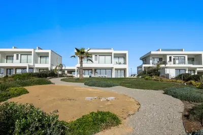 a large white building with a palm tree in front of it at Serenity Waves Villa 2 in Larnaka