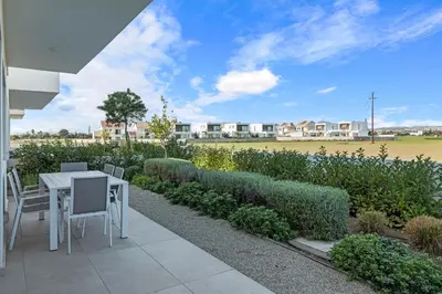 a patio with a table and chairs and a field at Serenity Waves Villa 11 in Larnaka
