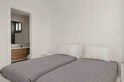 a white bedroom with two beds and a bathroom at Serenity Waves Villa 20 in Larnaka