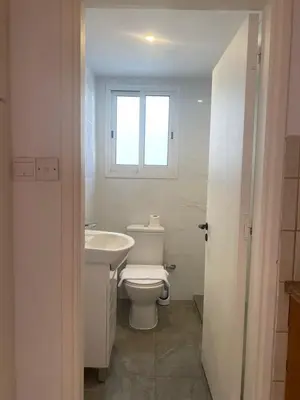 a bathroom with a toilet and a sink and a window at 1 bedroom flat 200m from beach in Limassol