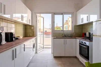 a kitchen with white cabinets and a large window at Central Escape in Limassol