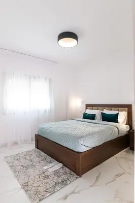a bedroom with a bed with blue sheets and a window at Kozakos Residence in Limassol