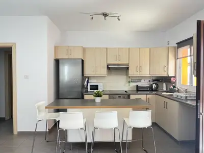 a kitchen with a island with white chairs in it at Wealthystays 3BR Terrace BBQ Villa with pool in Liopetri