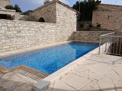a swimming pool in a stone building with a stone wall at Mountain View Oasis in Skarinou