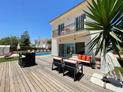 a deck with a couch and chairs and a house at Maeva villa in Ayia Napa