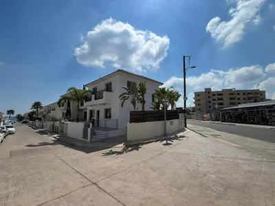a white house on a street with palm trees at Amour Et Citrons in Protaras