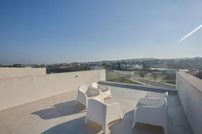a balcony with white chairs and a view of the city at Protaras Almaria Villa ALM03 in Protaras