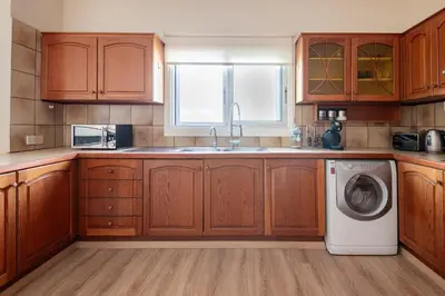 a kitchen with wooden cabinets and a washing machine at Central, renovated, fully equipped, spacious 3BD in Strovolos
