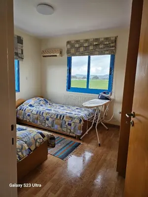 a bedroom with two beds and a table and a window at De Angelo Villa in Pyla