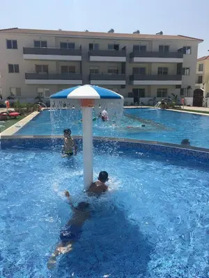 a group of people in a swimming pool with an umbrella at Mythical Sands Resort - Africa in Protaras