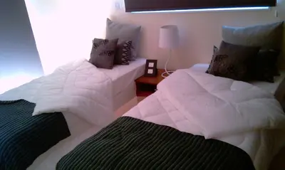 a bedroom with two beds with white sheets and a lamp at Mythical Sands Resort - Africa in Protaras