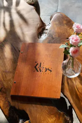 a wooden table with a sign on it with a vase of flowers at Lyhnos in Askas