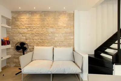 a white couch in a room with a brick wall at Family Fig Tree Bay House in Protaras